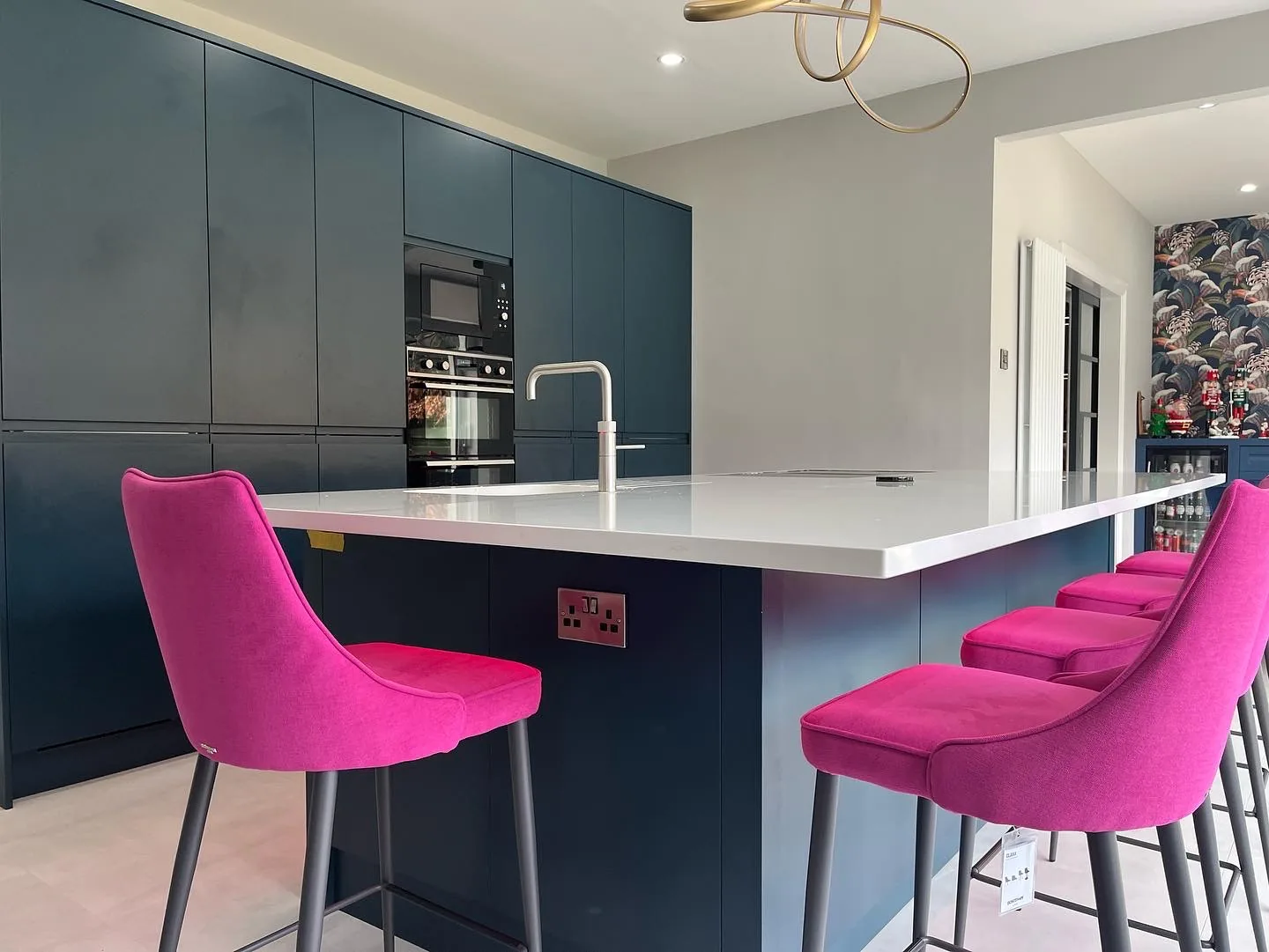 Navy handle-less kitchen island with magenta velvet bar stools
