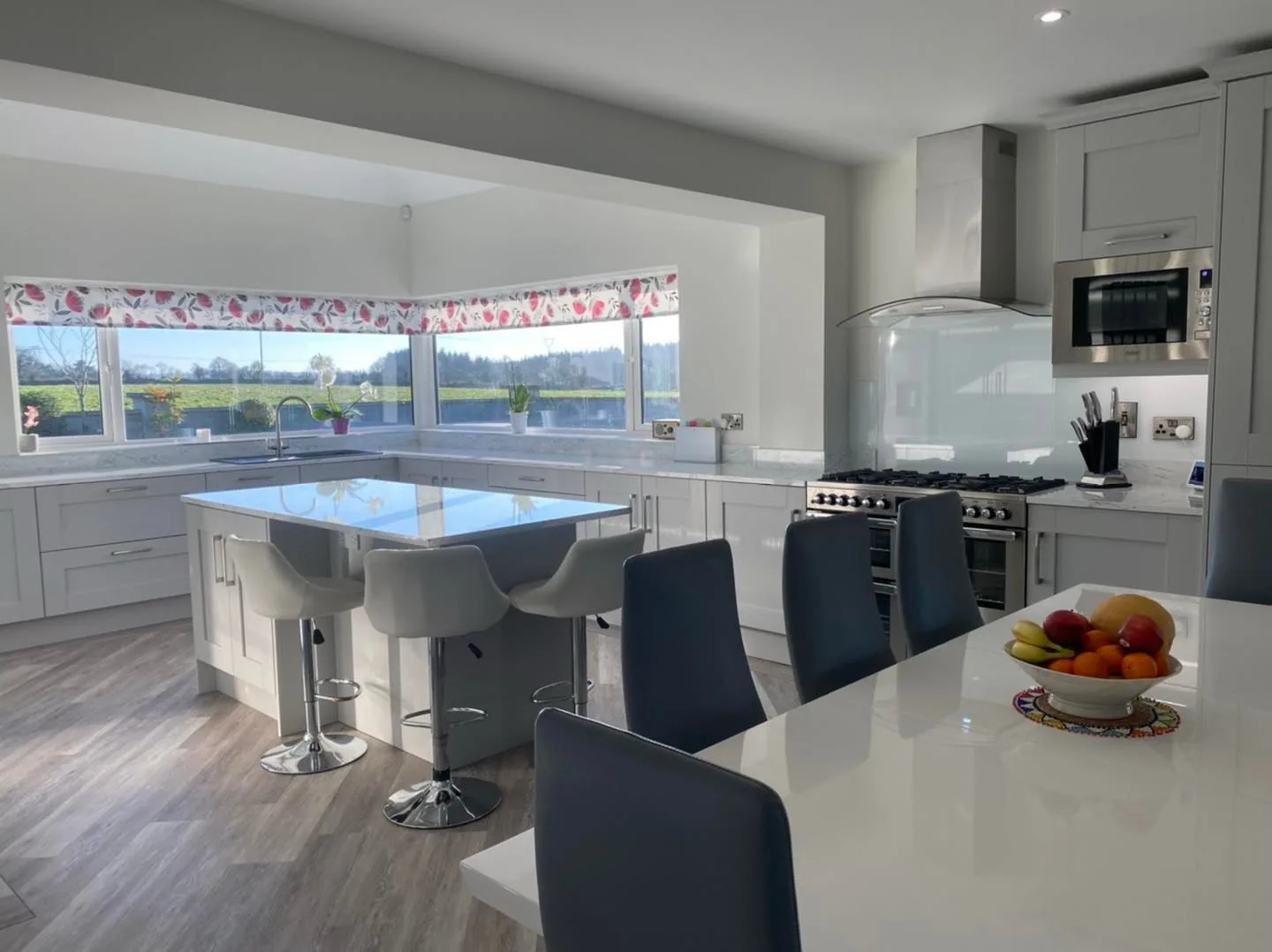 White shaker kitchen with double island and panoramic countryside bay window